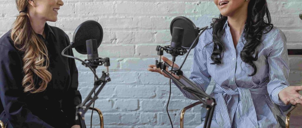 two women with microphone recording a podcast